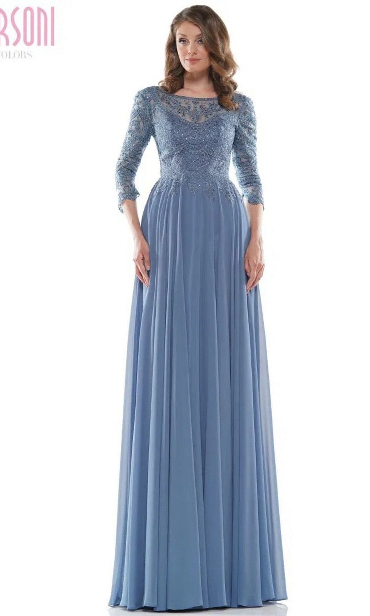 A woman wears the Marsoni M238SL long formal dress in slate blue, featuring a beaded lace bodice and a flowing chiffon A-line skirt.